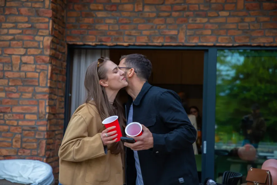 A couple kissing beside a brick wall