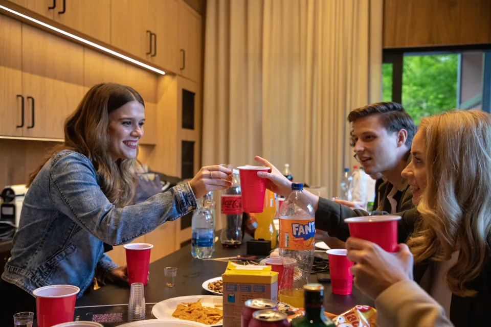 Guests clinking cups across a kitchen table